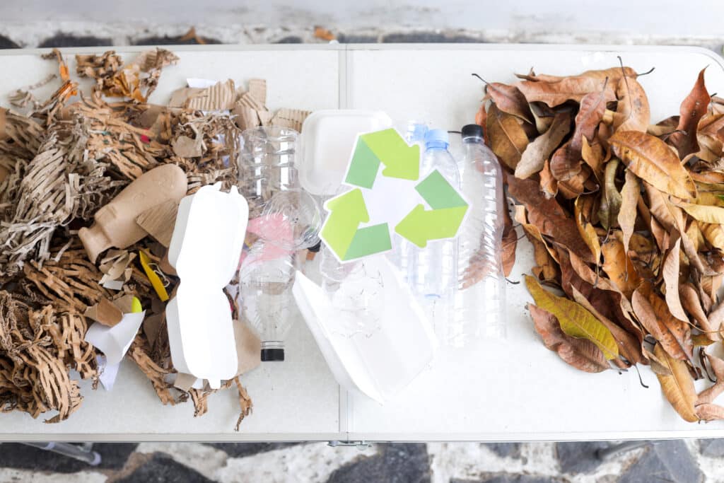 A collection of dry mixed recycling items - plastic, cardboard - and a recycling symbol